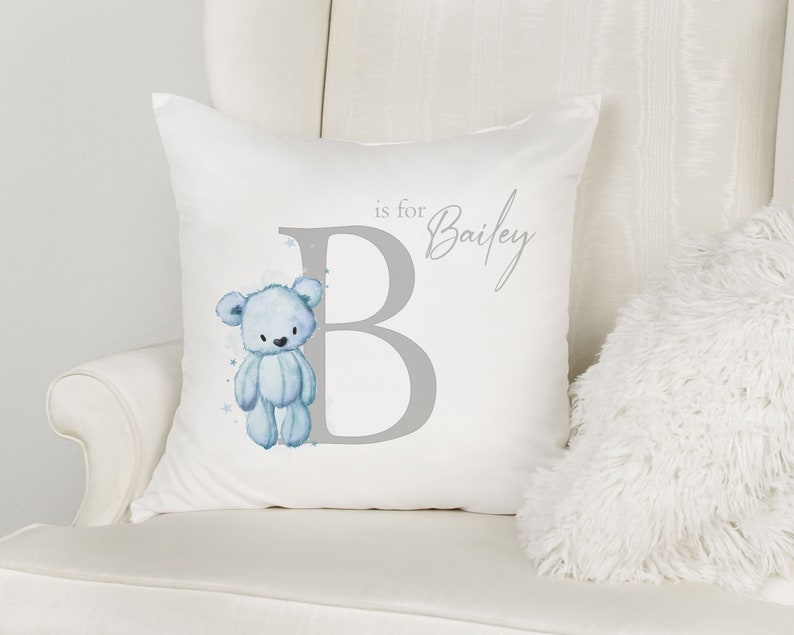 May include: A white pillow with a gray letter B and a blue teddy bear illustration. The text "B is for Bailey" is printed on the pillow.