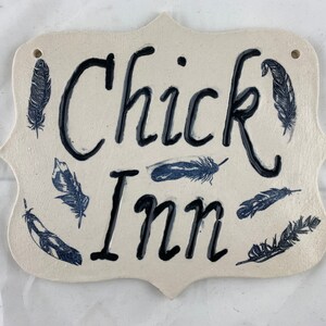 Chick Inn sign, black detail and feathers on white clay.