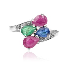 May include: A silver ring with a pear-shaped emerald, two pear-shaped rubies, and a pear-shaped sapphire. The ring is set with small diamonds.