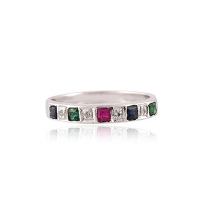 May include: A silver band ring with a row of colourful gemstones. The ring features alternating green, red, and blue gemstones with a single white diamond in the centre.