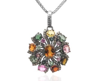 May include: A silver chain necklace with a pendant featuring a flower-shaped design with a variety of colorful gemstones, including green, pink, yellow, and orange.