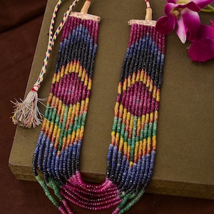 May include: A multi-strand necklace made of colorful gemstone beads. The necklace features rows of ruby, sapphire, emerald, and citrine beads.
