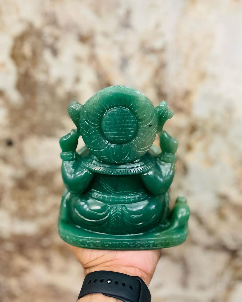 Pu&ograve; includere: Una statua di Ganesha in giada verde con dettagli intricati. La statua &egrave; seduta su una base e ha una parte posteriore rotonda e decorativa.