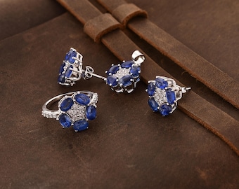 May include: A set of blue sapphire and white diamond jewelry, including a ring, a pendant, and a pair of earrings. The jewelry is set in silver.