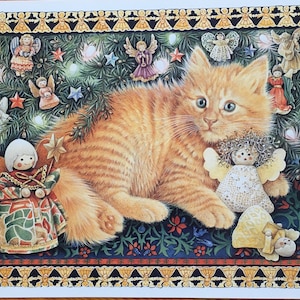 May include: A whimsical illustration of a ginger kitten surrounded by Christmas decorations. The artwork features a detailed border with angel figures, a Christmas tree, and several angel ornaments. The kitten has blue eyes and is the focal point of the image.