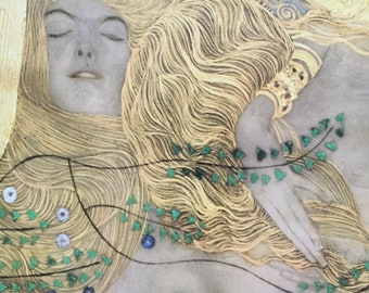 May include: Close-up of a painting featuring a woman with closed eyes and flowing blonde hair. The artwork incorporates gold leaf and decorative elements, including green and blue accents, creating a detailed and ornate composition.