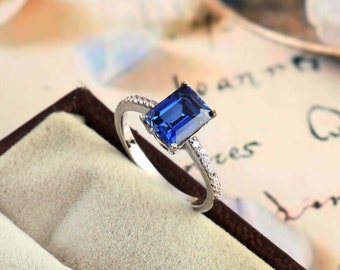 May include: A silver ring with a blue sapphire gemstone and small diamonds set in the band.