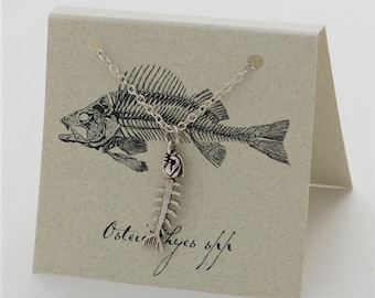 May include: A silver fish bone necklace with a fish skeleton illustration on a card that says "Osteichthyes sp/n".