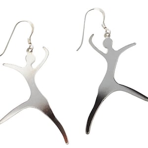 May include: A pair of silver earrings shaped like stylized figures. The figures are standing with their arms raised.