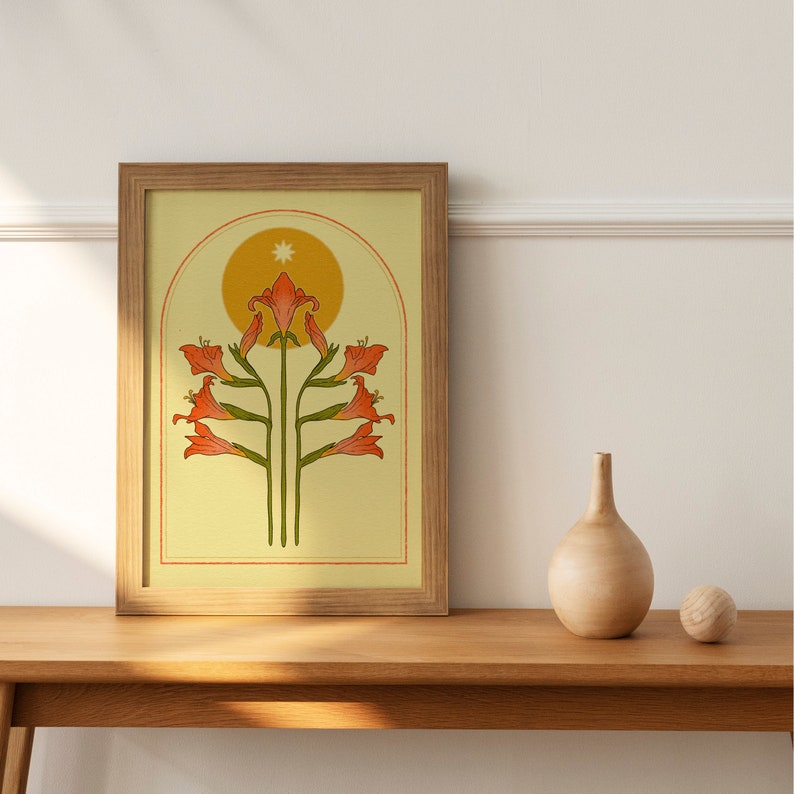 May include: A framed art print featuring a stylized floral design in shades of orange and green against a yellow background. The artwork is set within a wooden frame. A decorative vase and a wooden sphere sit on a wooden table.