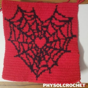 Op de afbeelding: Een rood geh&auml;keld vierkant met een zwart geh&auml;keld spinnenwebontwerp in de vorm van een hart. De tekst "PHYSOLCROCHET" is zichtbaar onderaan de afbeelding.