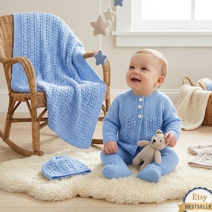 May include: A light blue knitted baby set consisting of a long-sleeved cardigan with three white buttons, matching footed trousers, and a beanie. A matching cable-knit blanket is draped over a wicker rocking chair, and a small beige teddy bear is included.