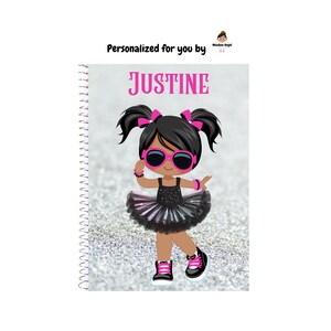 May include: A spiral-bound notebook with a glittery background. The cover features a cartoon girl with black hair, pink bows, sunglasses, and a tutu. The name "JUSTINE" is printed in pink. Text at the top reads "Personalized for you by".