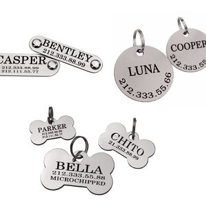 May include: Six silver dog tags with engraved names and phone numbers. The tags are in different shapes, including a bone, a circle and a rectangle.