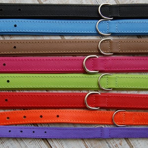 May include: Eight leather dog collars in different colours, including black, blue, brown, pink, green, red, orange, and purple. Each collar has a silver metal buckle.