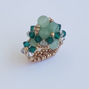 May include: A gold ring with a cluster of light green beads and dark green crystals.