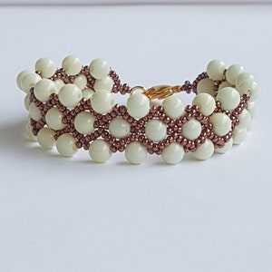 Bracciale da donna in perle di vetro bianco ecrù e perline MIYUKI color malva scuro. Bracciale fatto a mano. Chiusura a moschettone in ACCIAIO INOX. Bigiotteria.