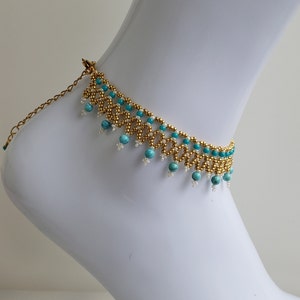 Pulsera de tobillo en turquesa ligeramente veteada y cuentas de semillas MIYUKI en blanco, dorado y turquesa. Cierre ajustable en acero inoxidable bañado en oro. Pulsera hecha a mano.