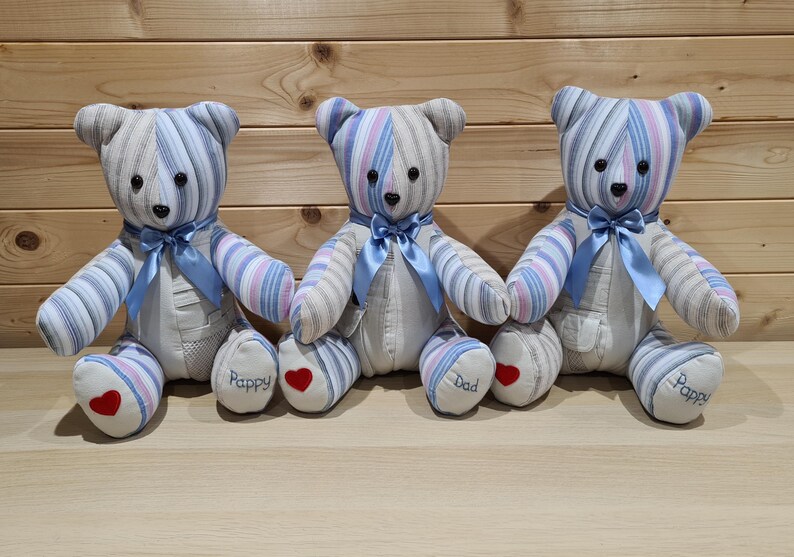 May include: Three handmade teddy bears with striped blue, white, and pink fabric. Each bear has a blue ribbon bow, black button eyes, and a red heart on the foot. One bear has "Dad" embroidered on its foot, and the others say "Pappy".