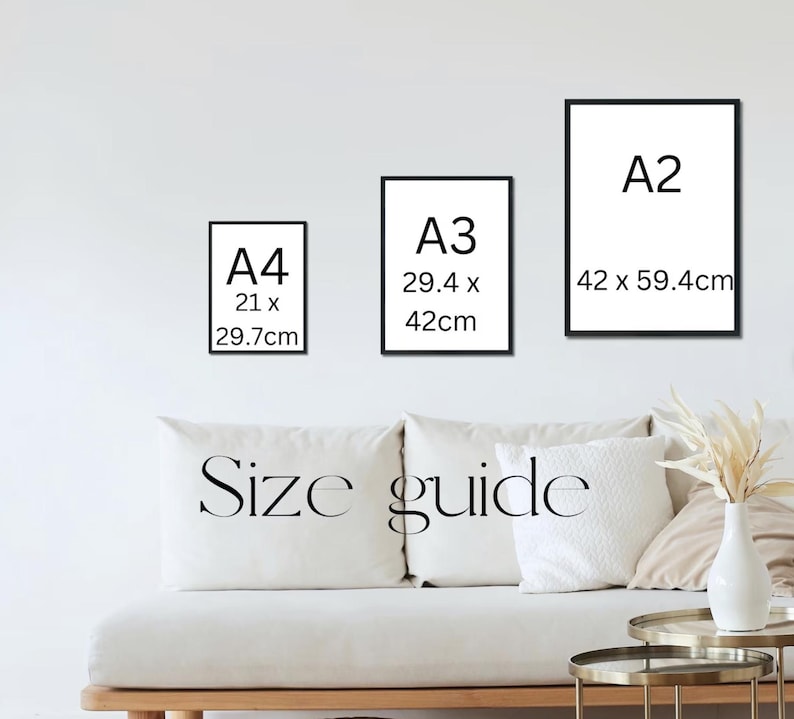 May include: Three framed art prints in black frames, labeled A4 (21 x 29.7cm), A3 (29.4 x 42cm), and A2 (42 x 59.4cm), against a white wall. Below, a white couch with pillows and the words "Size guide".
