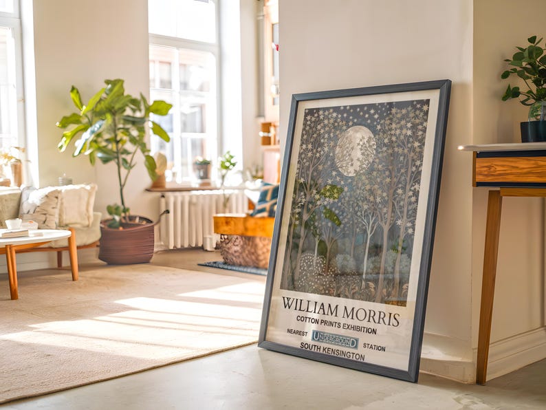 May include: A framed poster with a black frame and a white background. The poster features a black and white illustration of a moonlit forest with the text "William Morris Cotton Prints Exhibition" and "South Kensington" at the bottom.