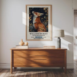 Op de afbeelding: Een vintage poster die reclame maakt voor een tentoonstelling van katoenen prints van William Morris in het Victoria and Albert Museum in South Kensington, Londen. De poster toont een rode vos tegen een achtergrond van een sterrenhemel.