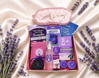 Puede incluir: Una caja de regalo que contiene un antifaz de satén rosa con el texto Sweet Dreams, máscaras de ojos autocalentables de lavanda, máscaras de retinol, spray de lavanda, bálsamo, aceite esencial, parches de gel y dos velas de té moradas.