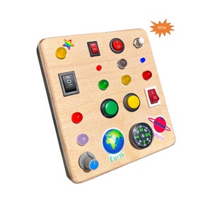 May include: A wooden board with various buttons, switches, and dials. The board features a compass, a globe, and a planet Saturn. The board is labeled "Earth" and "Saturn".
