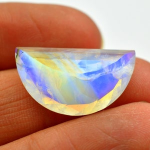 May include: A half-moon shaped iridescent gemstone with a rainbow of colors, including blue, yellow, and green.