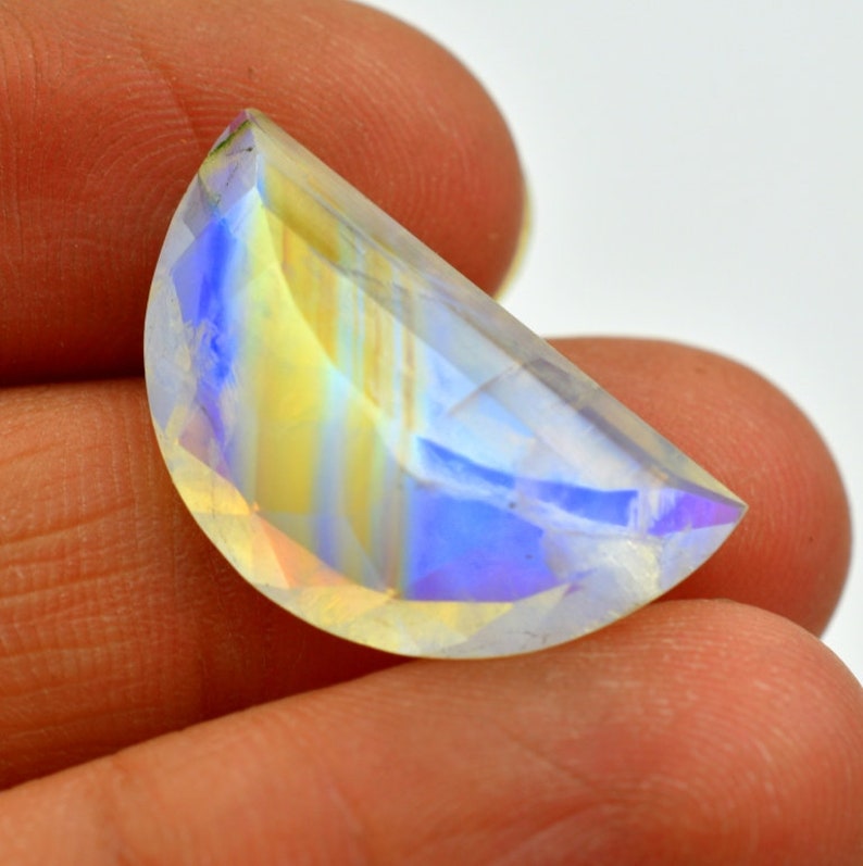 May include: A half-moon shaped iridescent gemstone with a rainbow of colors, including blue, yellow, and purple.