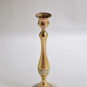 Pode incluir: Um castiçal de metal dourado com uma incrustação de madrepérola branca em torno da base e no meio do caule.