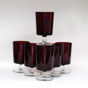 May include: Set of six dark red stemmed glasses with a clear glass base. The glasses are arranged in a pyramid shape.
