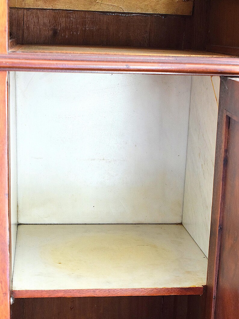May include: An open wooden cabinet with a light interior. The cabinet has a dark brown exterior and a light-colored interior. The interior has a shelf and a back panel. The cabinet is empty.