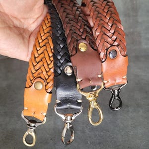 May include: Three braided leather straps with metal clasps. The straps are brown, black, and a lighter brown. The straps are woven together in a pattern.