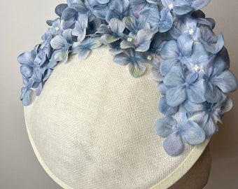 Splendido fascinator tondo in crema Sinamay con petali di ortensia blu fiordaliso ombreggiato Gare nuziali KittyMay.online