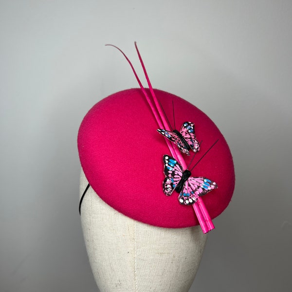 Un élégant fascinateur en feutre rose fuchsia avec des papillons et des plumes roses, chapeau mariage courses KittyMay.Online