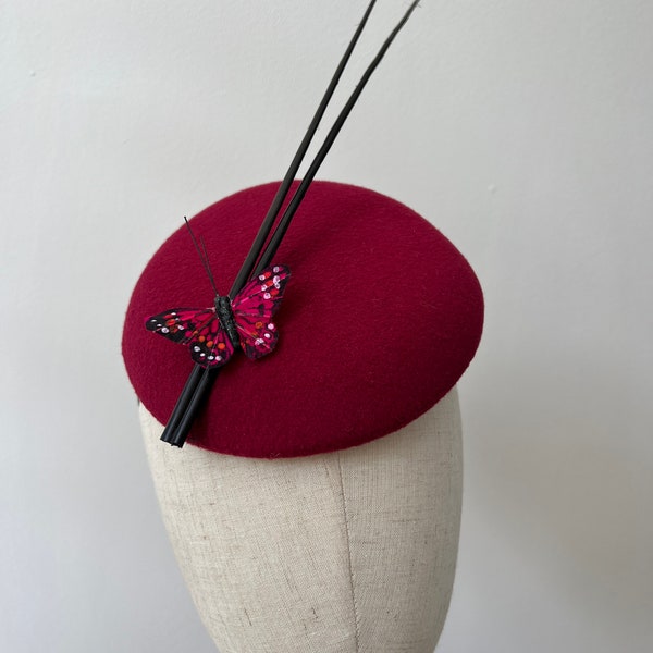 Ein eleganter burgunderfarbener Filz-Fascinator mit Schmetterling und schwarzem Federkiel-Hut. Hochzeitsrennen KittyMay.Online