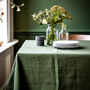 a table with a green linen table cloth and a vase of flowers