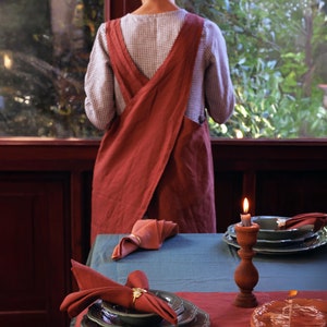 May include: A blue tablecloth with a set of three green plates and a red napkin. A lit candle in a wooden holder is on the table.