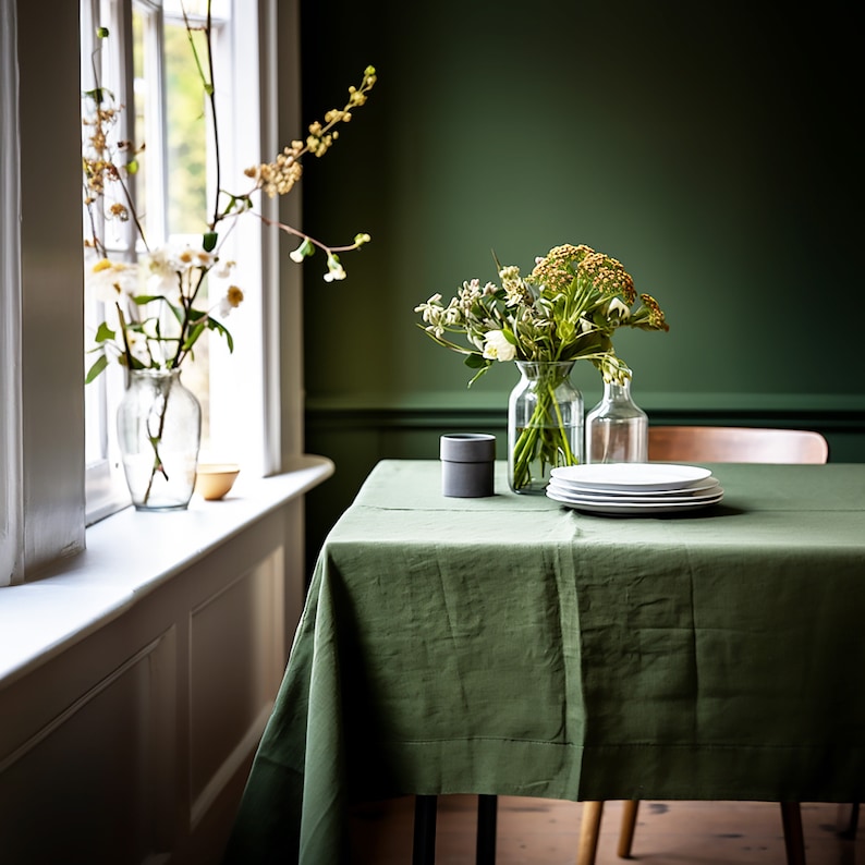 a table with a green linen table cloth and a vase of flowers