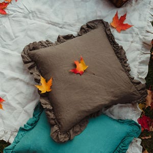Puede incluir: Dos almohadas decorativas con bordes con volantes. La almohada superior es de lino marr&oacute;n oscuro con un dise&ntilde;o de hoja de oto&ntilde;o. La almohada inferior es de lino azul turquesa.