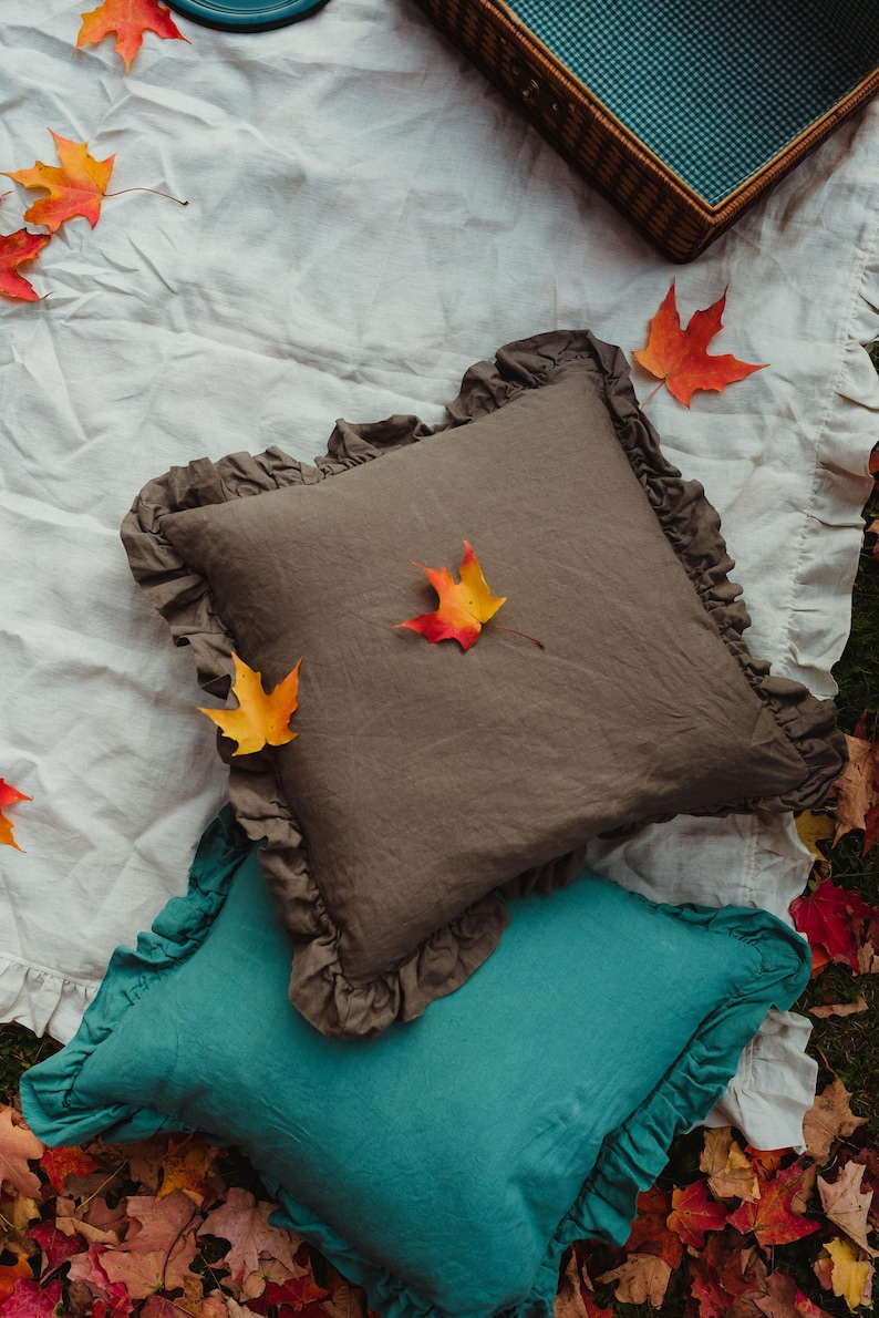 Puede incluir: Dos almohadas decorativas con bordes con volantes. La almohada superior es de lino marr&oacute;n oscuro con un dise&ntilde;o de hoja de oto&ntilde;o. La almohada inferior es de lino azul turquesa.