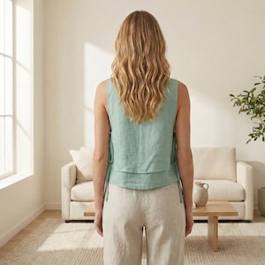 Puede incluir: Un top sin mangas verde claro con lazos, combinado con pantalones de lino beige. El conjunto lo lleva una persona con pelo largo y rubio ondulado. El fondo incluye un sof&aacute; beige, una mesa de madera y una planta en maceta.