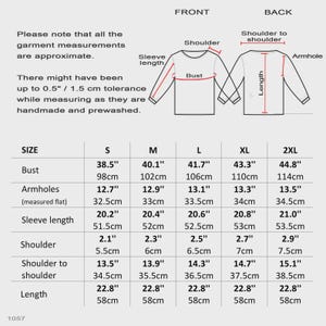 May include: A garment size chart featuring a diagram of a long-sleeve shirt with labels for shoulder, sleeve length, bust, armhole, and length. A table provides measurements in inches and centimeters for sizes S, M, L, XL, and 2XL, including a 0.5-inch tolerance note.