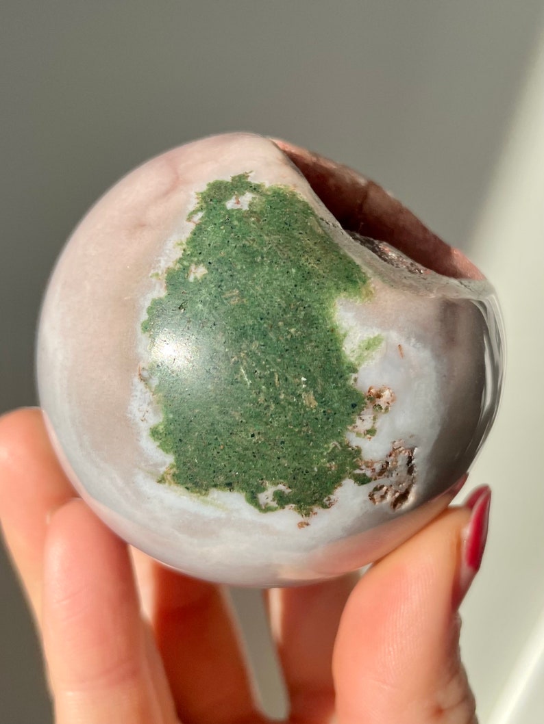 May include: A smooth, white and pink sphere with a large green patch. The sphere has a natural, polished finish.