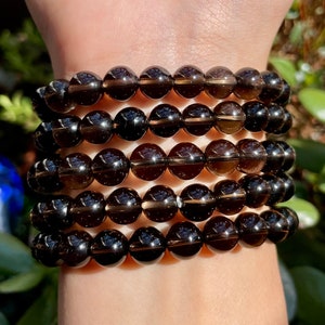 Peut inclure: Un ensemble de quatre bracelets en pierres précieuses brunes avec des perles rondes. Les bracelets sont en quartz fumé.
