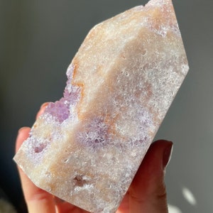 May include: A large, clear, amethyst crystal with a rough, textured surface. The crystal is a light purple color with hints of white and brown. It is a natural, raw crystal.