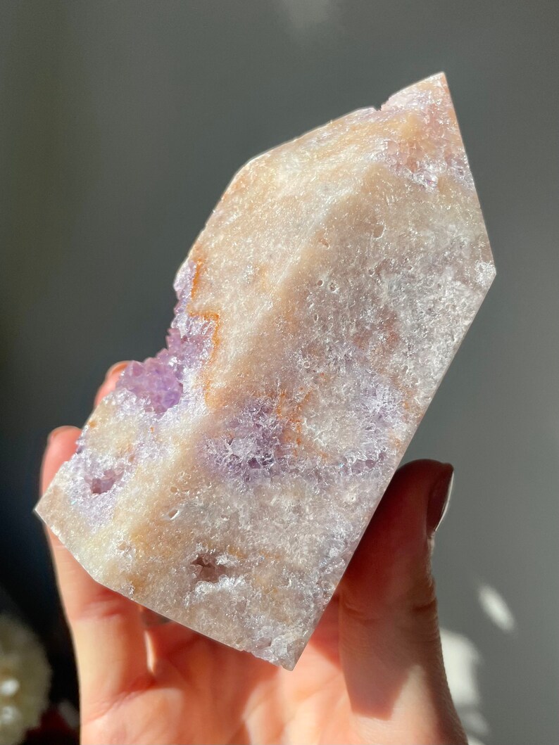May include: A large, clear, amethyst crystal with a rough, textured surface. The crystal is a light purple color with hints of white and brown. It is a natural, raw crystal.