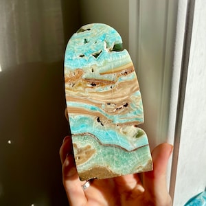 May include: A blue and brown banded agate crystal with a unique, natural shape. The crystal is polished and has a smooth, glassy surface.