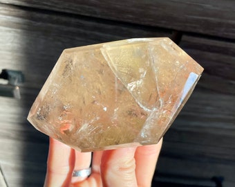 May include: A large, clear, faceted, golden citrine crystal with a geometric shape.